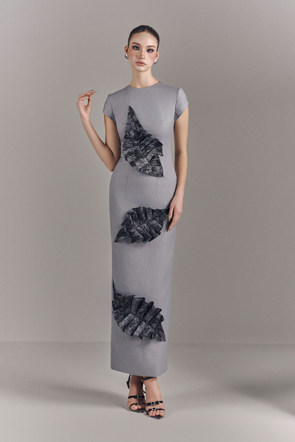 Woman wearing a gray dress with black floral patterns on a plain background