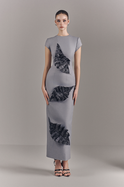 Woman wearing a gray dress with black floral patterns on a plain background