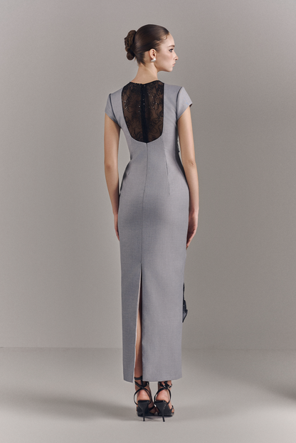 Woman wearing a gray dress with a black lace back on a plain background
