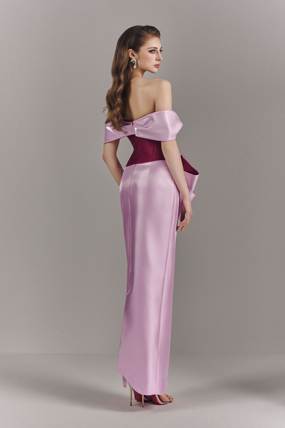Woman wearing a two-tone off-shoulder evening gown on a plain background