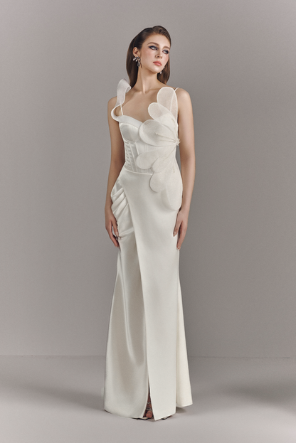 Woman wearing a white evening gown with floral details on a gray background