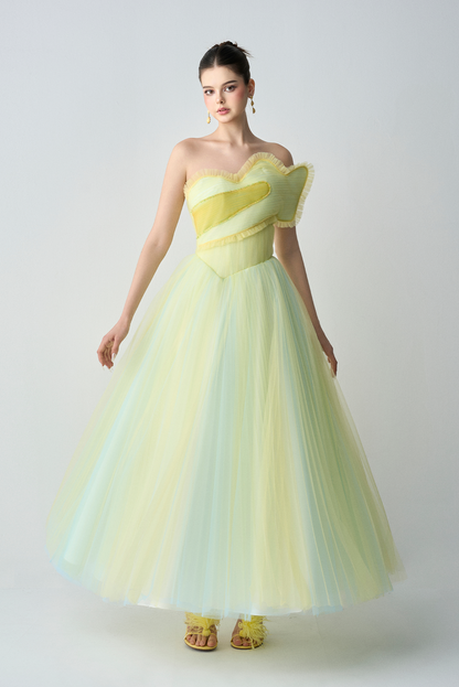 Woman wearing a strapless, light green and yellow dress against a white background
