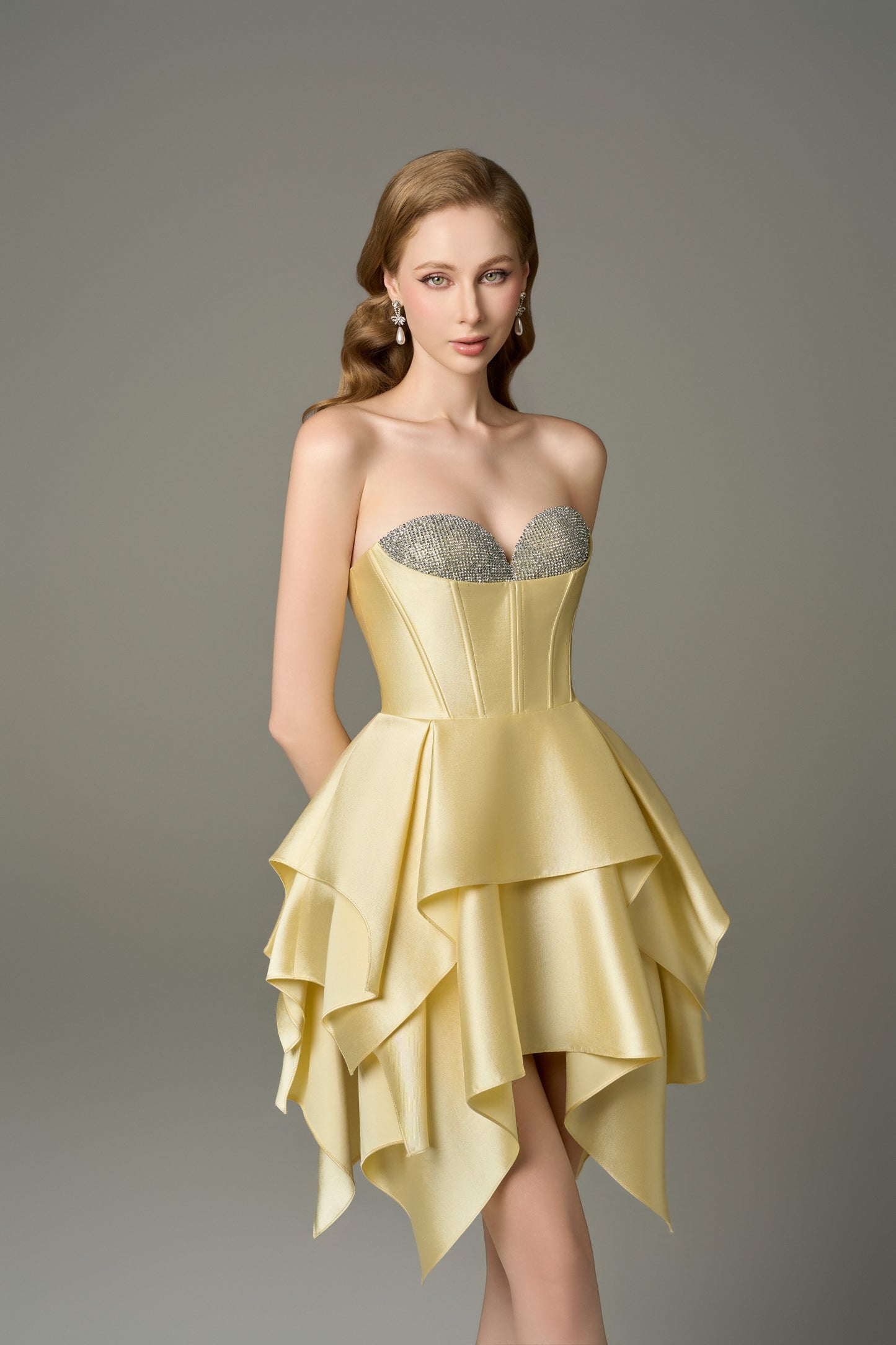 A close-up front view of a Soleil yellow mini dress, highlighting its sweetheart neckline with handcrafted crystal embellishments, corset bodice, and multi-layered skirt.