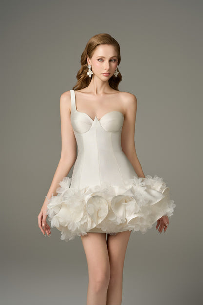 A front view of a short, white, one-shoulder mini dress, designed with a structured bustier and a ruffled, floral-embellished puffy skirt.