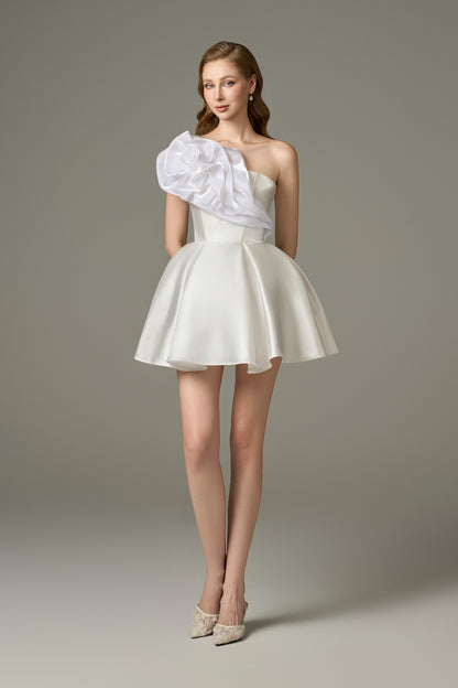  A full-length front view of a graceful white flared micro-mini dress featuring a bandeau neckline, one-shoulder strap adorned with handcrafted floral embellishments, a corset bodice, and a voluminous, fluffy mini skirt.