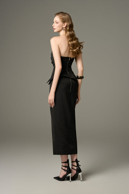 A back view of a Noir black stripe tweed set, showcasing the figure-hugging fit of the bandeau top and the long skirt.