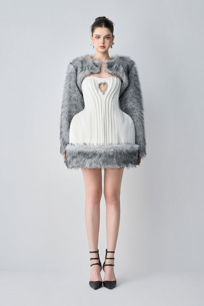 Woman wearing a white dress with a fur-trimmed coat on a gray background