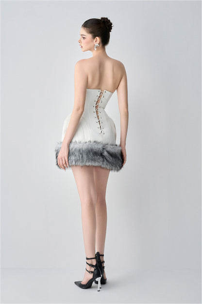 Woman wearing a strapless dress with fur trim on a plain background