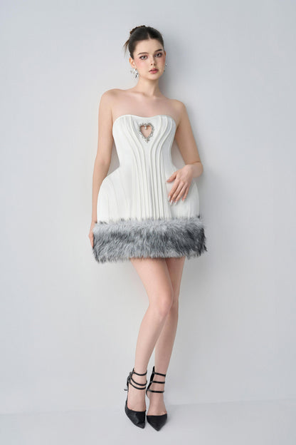 Woman wearing a white strapless dress with feathered hem against a plain background