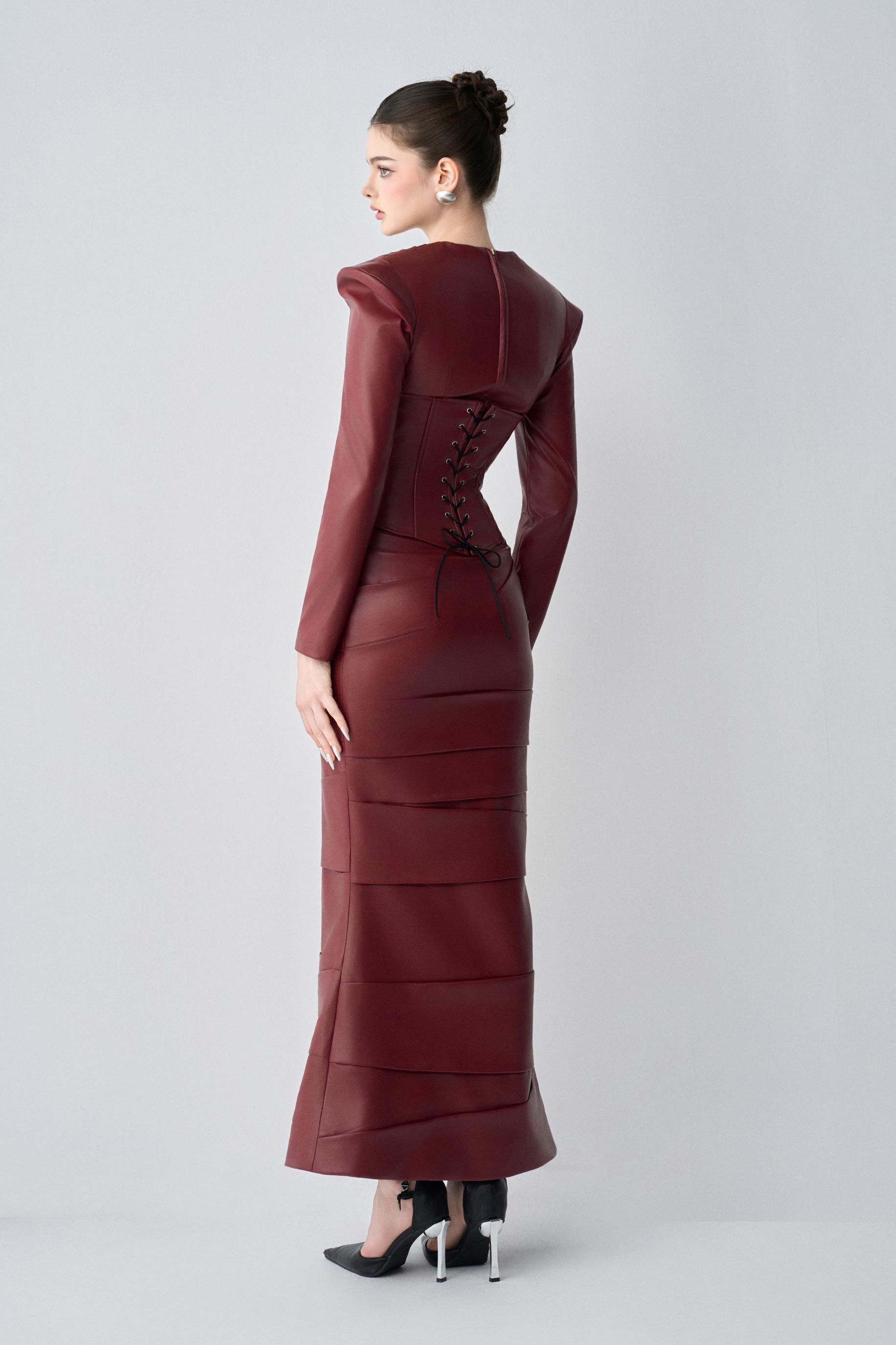 Maroon leather dress with a fitted silhouette and lace-up details on a white background