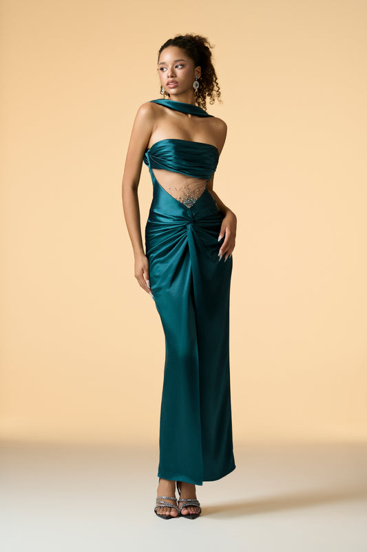 A sleeveless maxi dress in a dark, shimmering fabric, featuring a bandeau neckline with a scarf neck wrap. The dress has a draped front and a mesh waist, with hand-embellished crystals on the bodice.