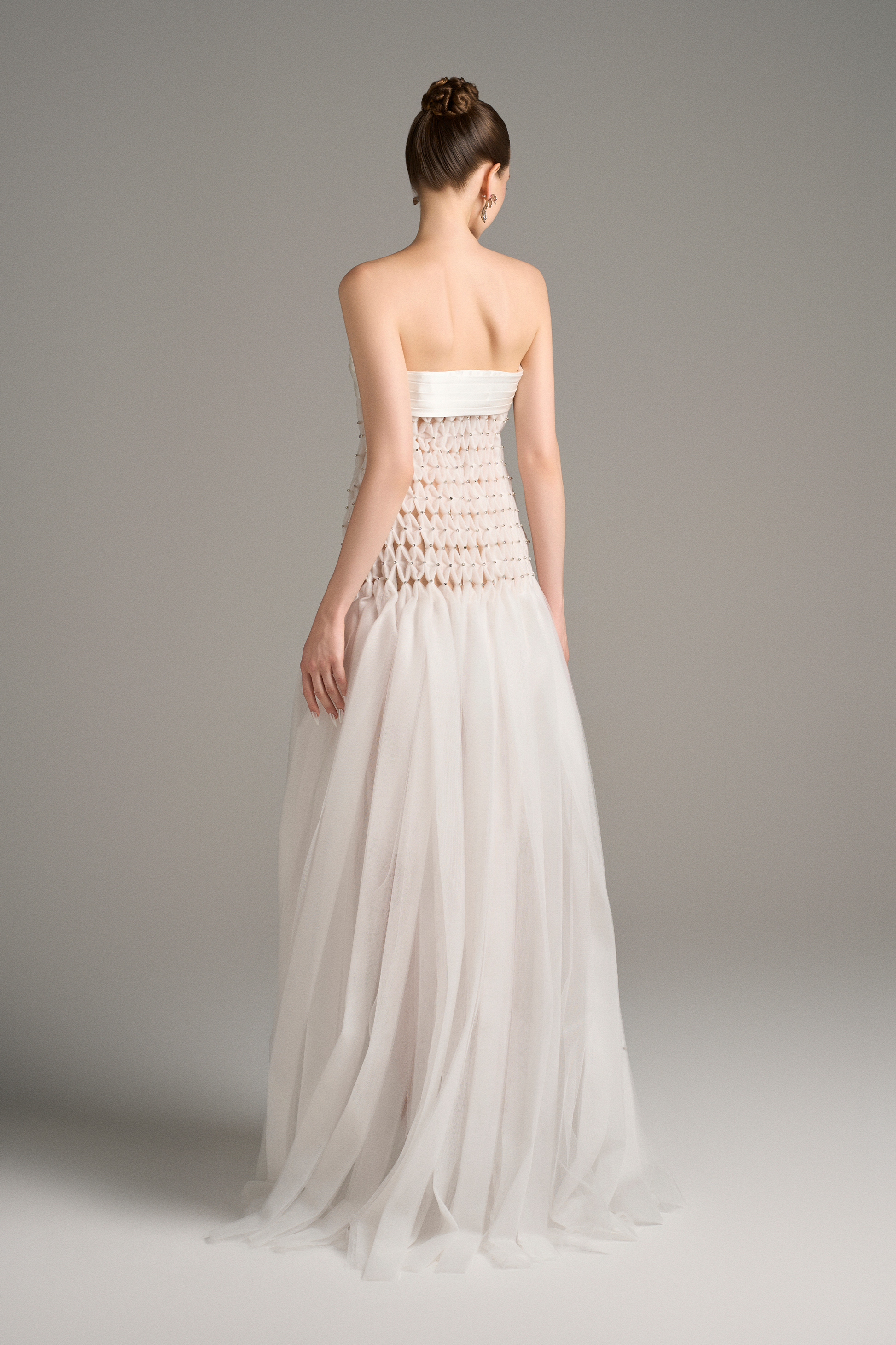 Back view of strapless white maxi dress with see-through criss-cross detail and mesh skirt