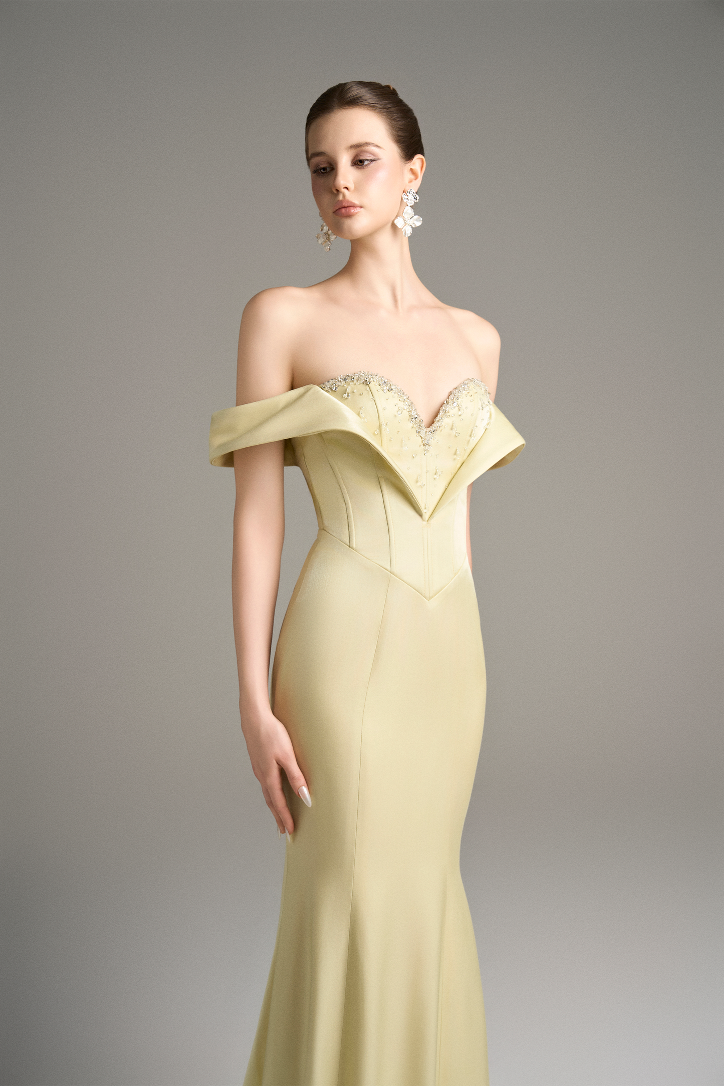 Close-up of a model in a yellow off-shoulder moiré silk gown, highlighting the sweetheart neckline, crystal beaded embellishments, and corset bodice.