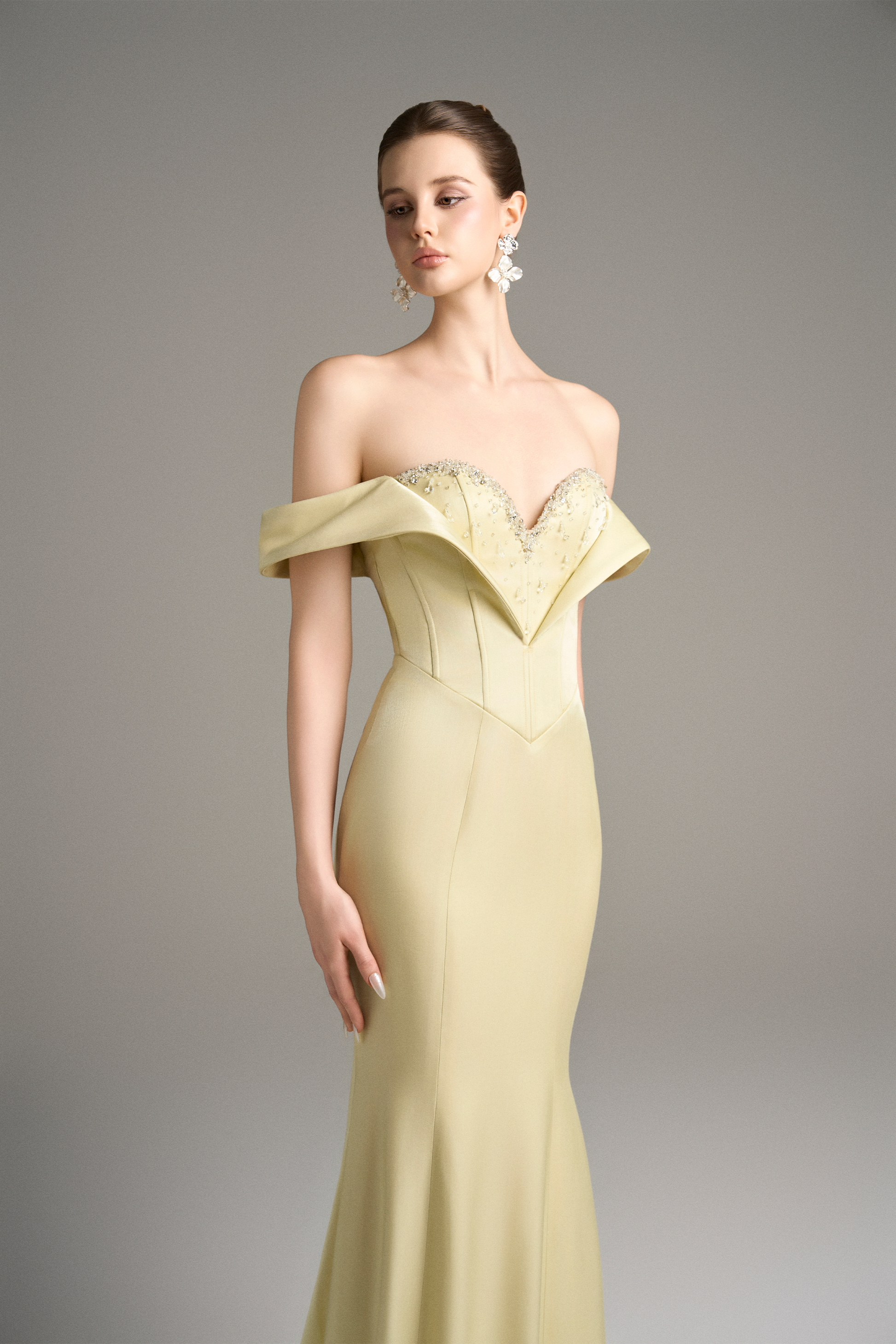 Close-up of a model in a yellow off-shoulder moiré silk gown, highlighting the sweetheart neckline, crystal beaded embellishments, and corset bodice.