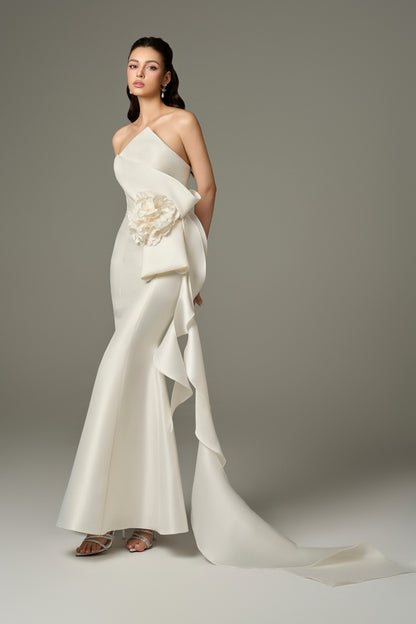  close-up front view of an Isabella ivory acetate fishtail gown, highlighting the bandeau neckline, draped details, and the prominent, handcrafted 3D floral embellishment on the hip.