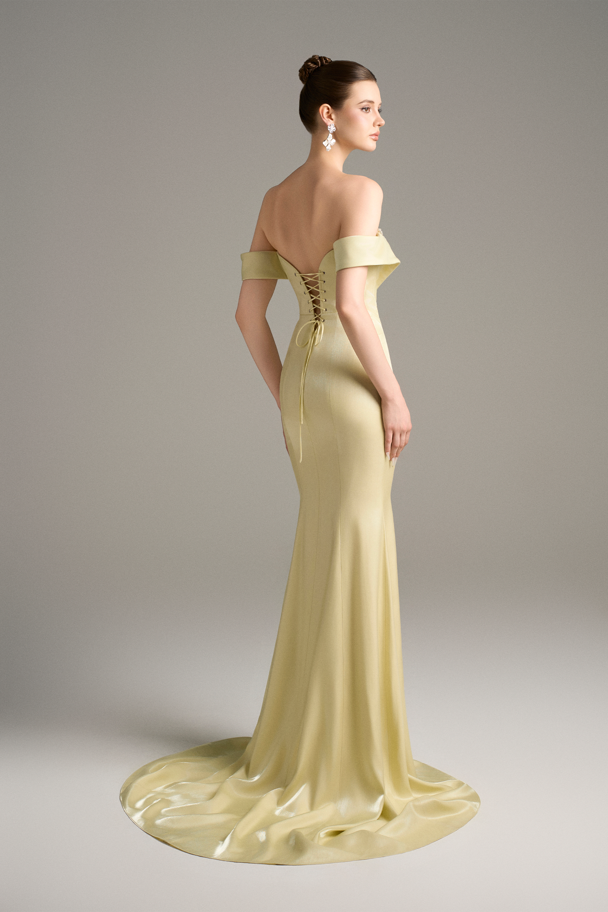 Back view of a model in a yellow silk mermaid gown, showcasing the lace-up corset back, off-shoulder sleeves, and elegant train.