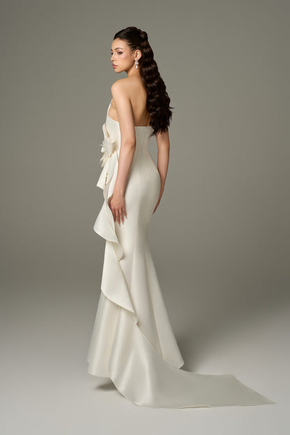 A back view of an Isabella ivory acetate fishtail gown, showcasing its figure-hugging silhouette, draped details, and the dramatic flair of the fishtail skirt.