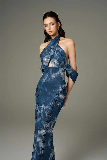 A close-up front view of a chic modest blue cotton denim halter tie-dye maxi dress, highlighting its halter neckline, off-shoulder detail, and front criss-cross black laces.