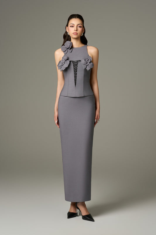 A full-length front view of a contour grey dual-style maxi dress with a bodycon fit, featuring a halter neckline, sleeveless design, and a corset top with lace-up detail and handcrafted floral embellishments.