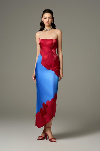 A full-length font view of a Darling color mix taffeta maxi dress, displaying its bodycon fit, sleeveless design, and the dramatic, asymmetric silhouette created by the heart-shape embellishments and flowing skirt.