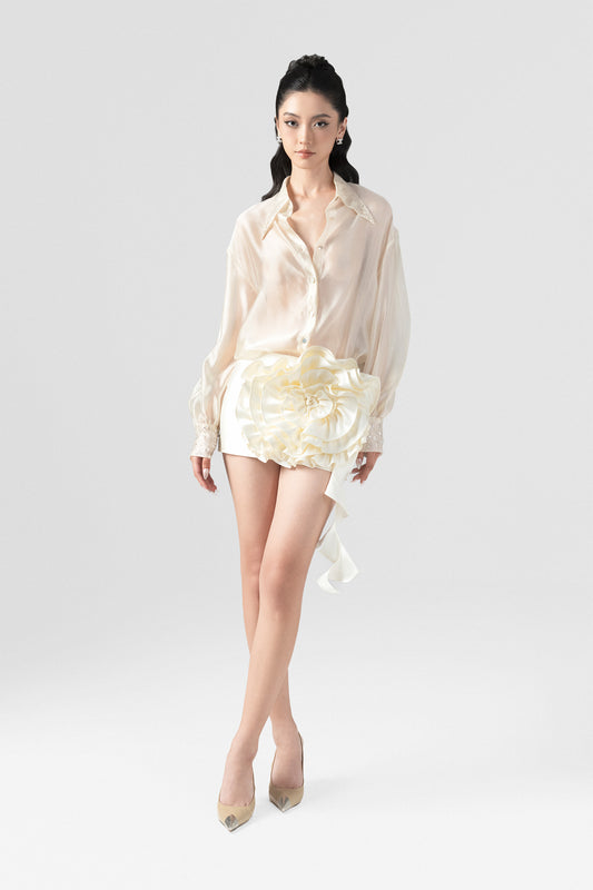 A beige set, featuring a silk shirt with  beading on the collar, cuffs and a bodycon mini skirt with a large floral accent. 