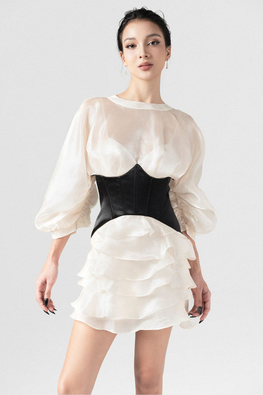 The beige mini dress in silk organza, with long puff sleeves,  open back, black corset detailing, and a voluminous skirt.
