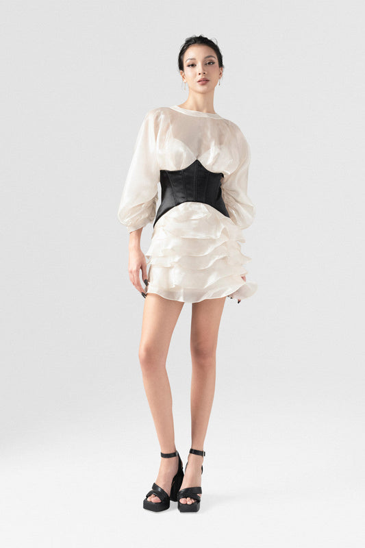 The beige mini dress in silk organza, with long puff sleeves,  open back, black corset detailing, and a voluminous skirt.