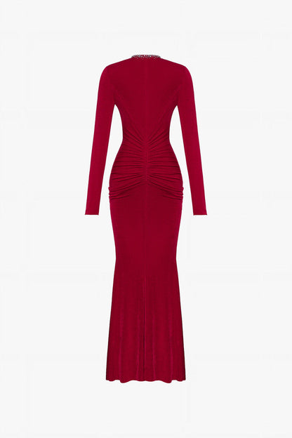 The red maxi dress in spandex, featuring a deep V-neckline with embellished crystals and ruching on both sides.