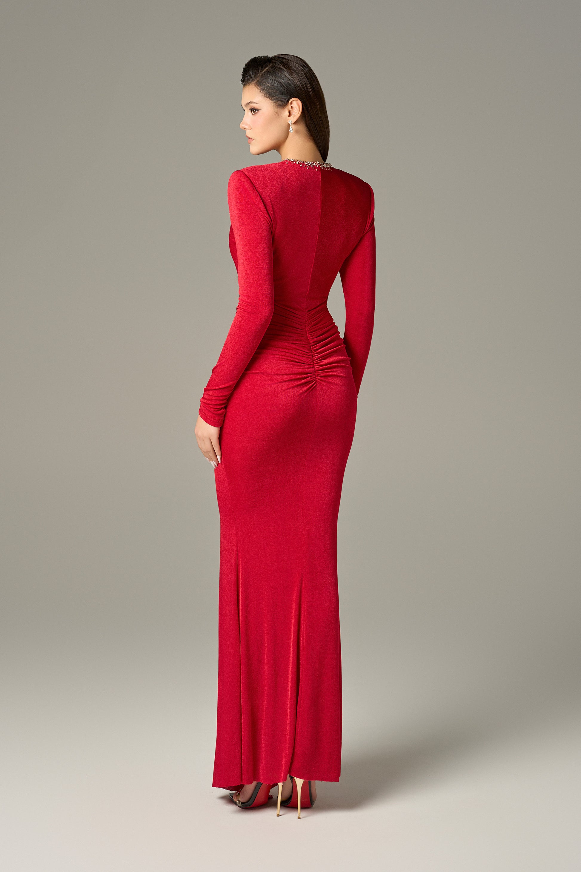 The red maxi dress in spandex, featuring a deep V-neckline with embellished crystals and ruching on both sides.