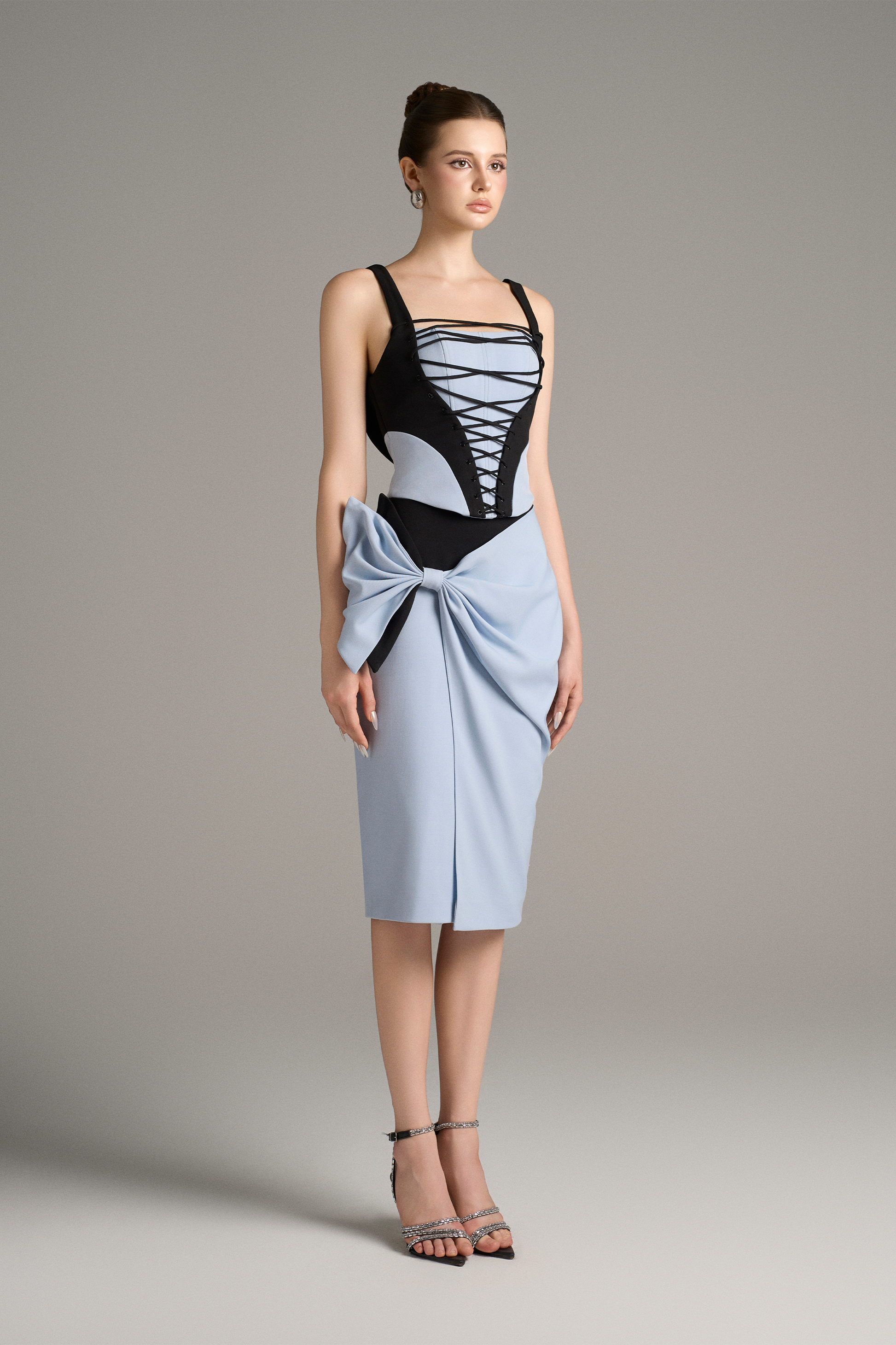 Model wearing a black and blue dress with a bow detail on a plain background