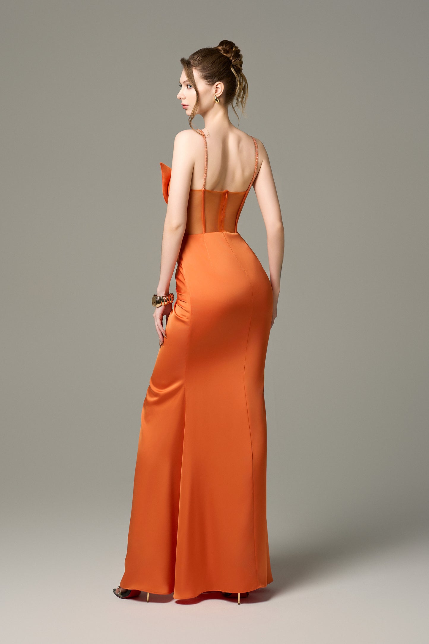 The orange gown features a form-fitting silhouette and crystals adorning the straps. 