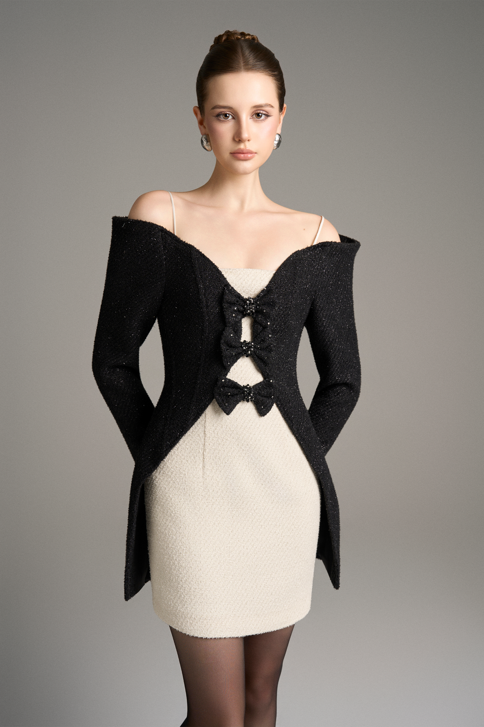 Woman wearing a black off-shoulder jacket over a white dress