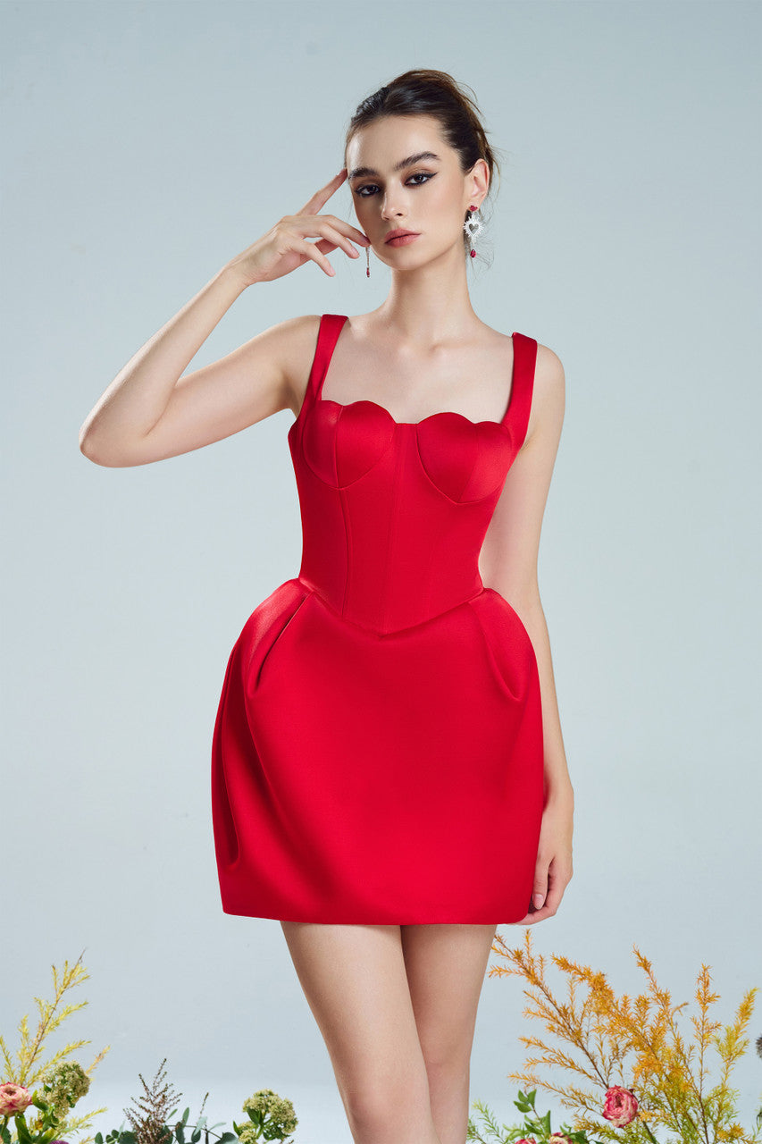 A red mini dress in taffeta, designed with a romantic heart-shaped neckline and puffed hips with structured pleats.