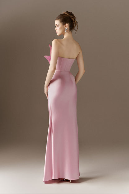 The back view of a pink, figure-hugging maxi dress, showcasing its flowing silhouette and the off-shoulder open neckline from behind.
