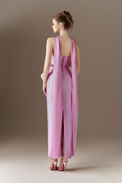 The back view of a pink strapless maxi dress, showing a back slit and a long, flowing cape attached at the shoulders, extending to the floor.